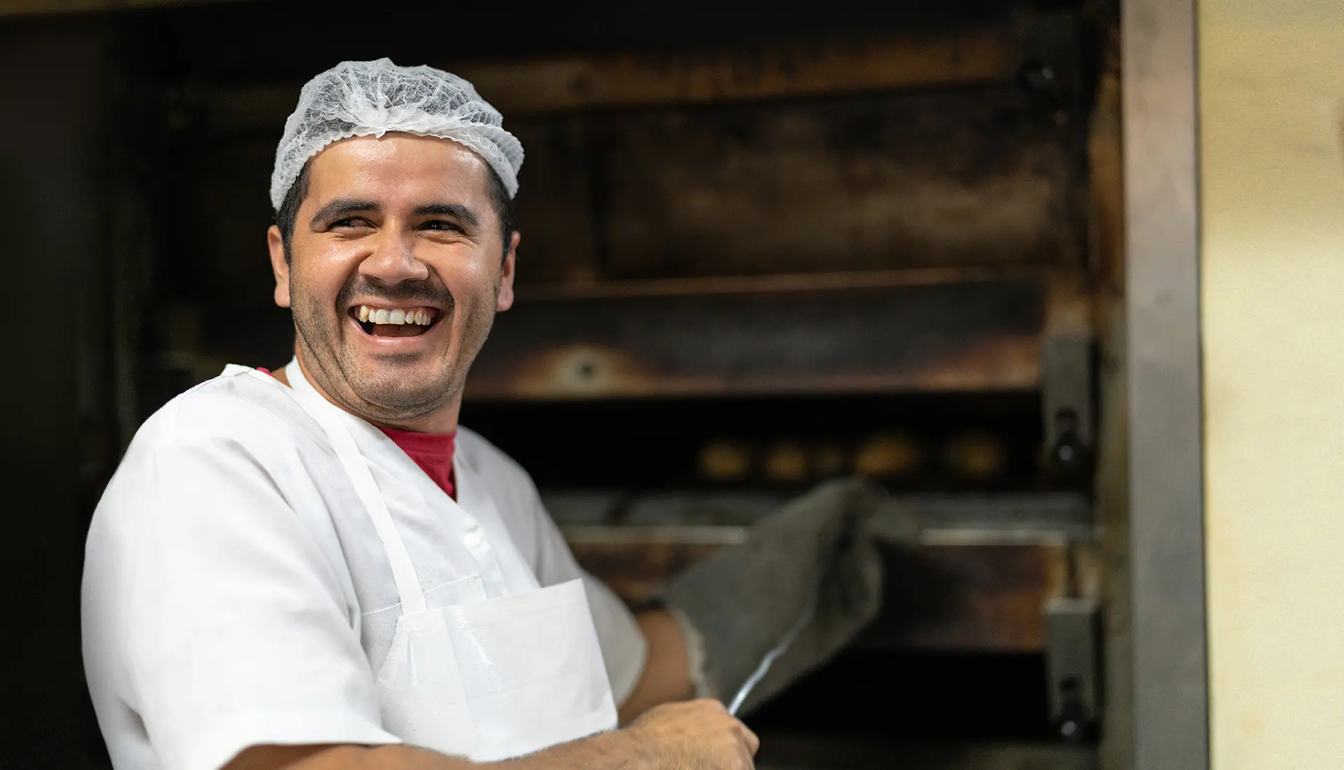 A Coupland's baker grinning as he unloads freshly baked bread from the oven