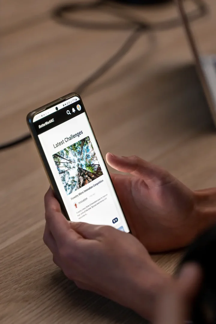 Person holding a smartphone showing a screen titled “Latest Challenges” with colorful icons and text.