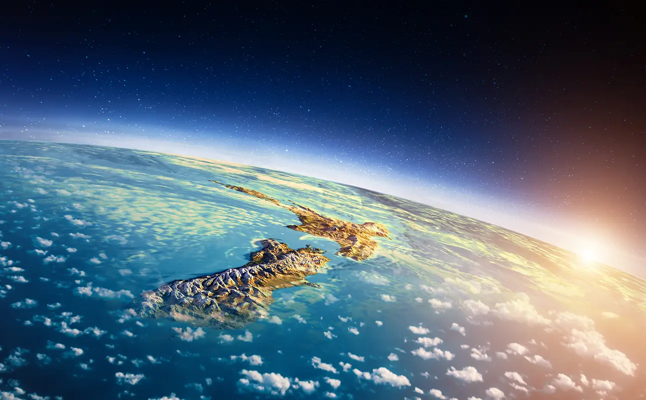 Satellite view of New Zealand at sunrise, showing both islands surrounded by ocean and clouds.