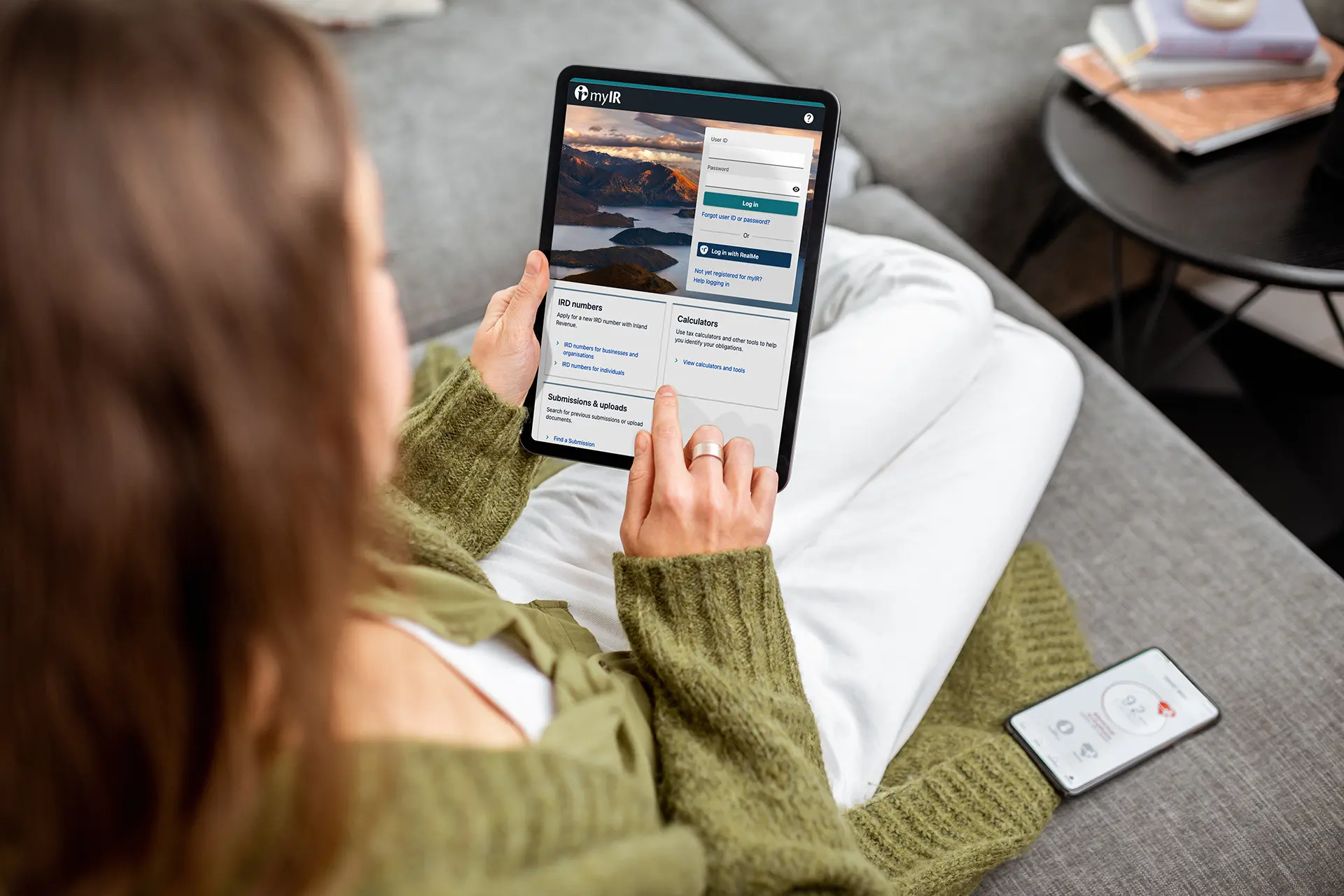 Woman logging into the Inland Revenue website on a tablet while sitting on a couch.